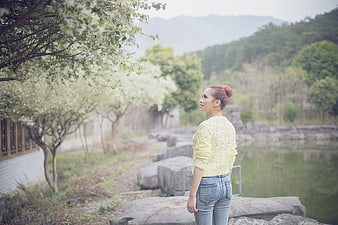 Woman in yellow sweater standing by a misty lake in spring