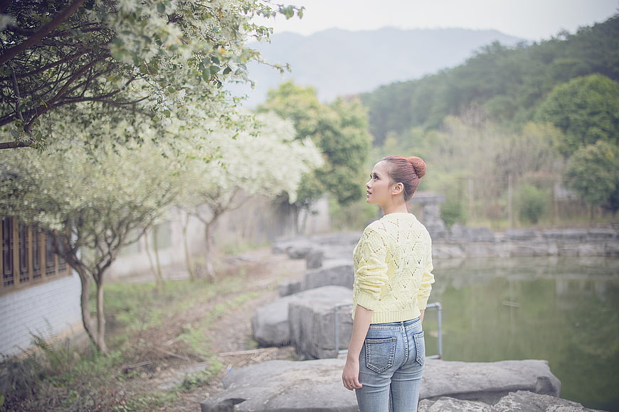 Woman in yellow sweater standing by a misty lake in spring