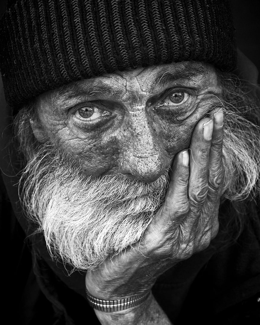 Black and white portrait of elderly bearded man with hand on face