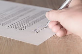 Hand signing a legal contract document with pen