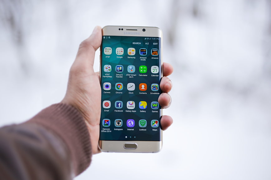 Hand holding Samsung Galaxy smartphone in snowy winter landscape