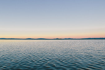Serene Lake Sunset with Distant Mountains and Calm Water