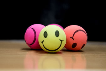 Colorful smiley face balls on wooden surface