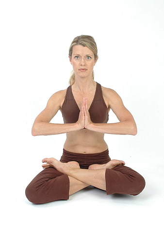 Woman in lotus yoga pose with hands in prayer position on white background