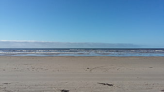 Wide Empty Sandy Beach with Blue Sky and Ocean Waves