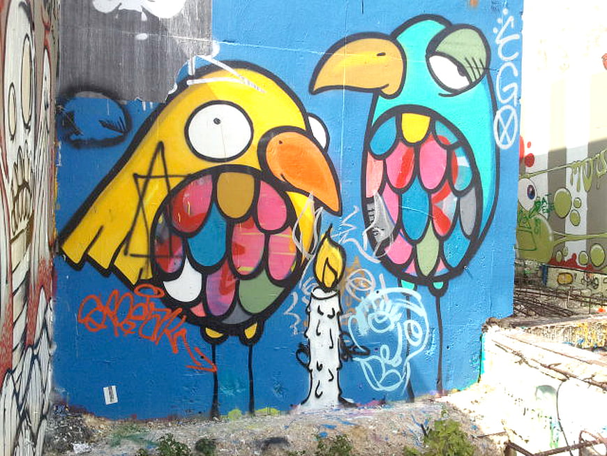 Colorful graffiti mural of cartoon birds on blue wall