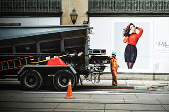 Construction worker standing near truck and fashion billboard