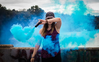 Woman holding blue smoke grenade outdoors