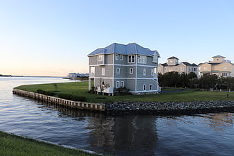 Modern waterfront house on a grassy peninsula at dusk
