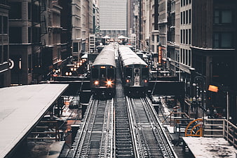 Two elevated trains on parallel tracks in a snowy city