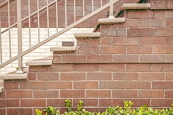 Red brick stairs with metal railing and green plants