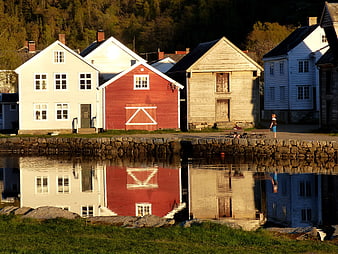 Colorful wooden houses reflecting in calm water at sunset