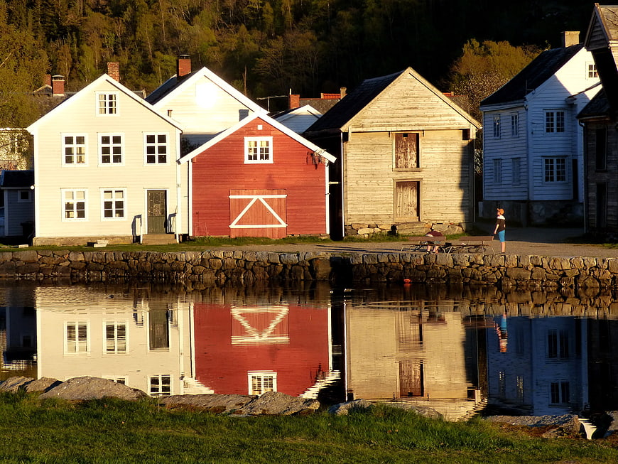 Colorful wooden houses reflecting in calm water at sunset