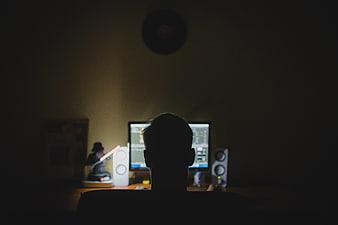 Silhouette of person working at computer desk at night