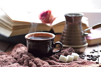 Cozy steaming coffee cup with Turkish cezve and books