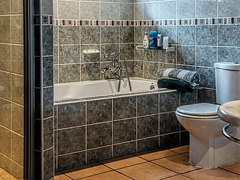 Modern bathroom interior with grey tiles and white bathtub