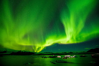 Vibrant Green Aurora Borealis Over Rocky Shoreline