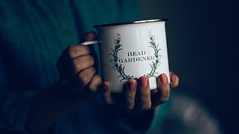 Woman holding white enamel mug with Head Gardener text