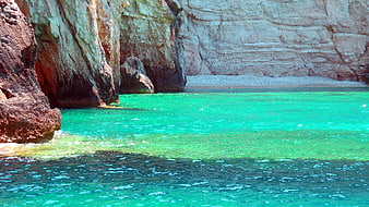 Vibrant turquoise sea water in a rocky cove with layered cliffs