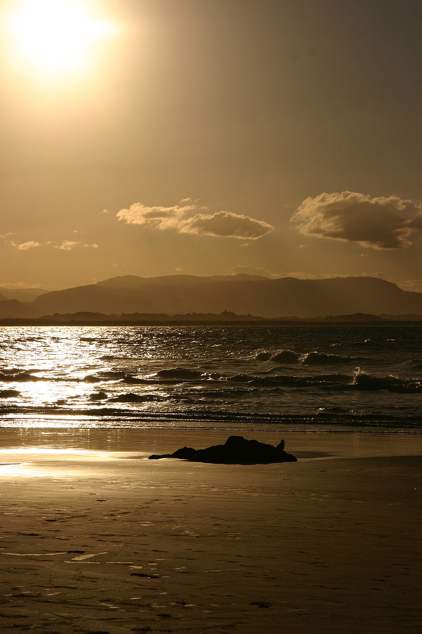 Golden Sunset Over Ocean Beach with Silhouetted Rock