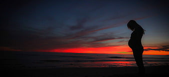 Silhouette of Pregnant Woman on Beach at Sunset