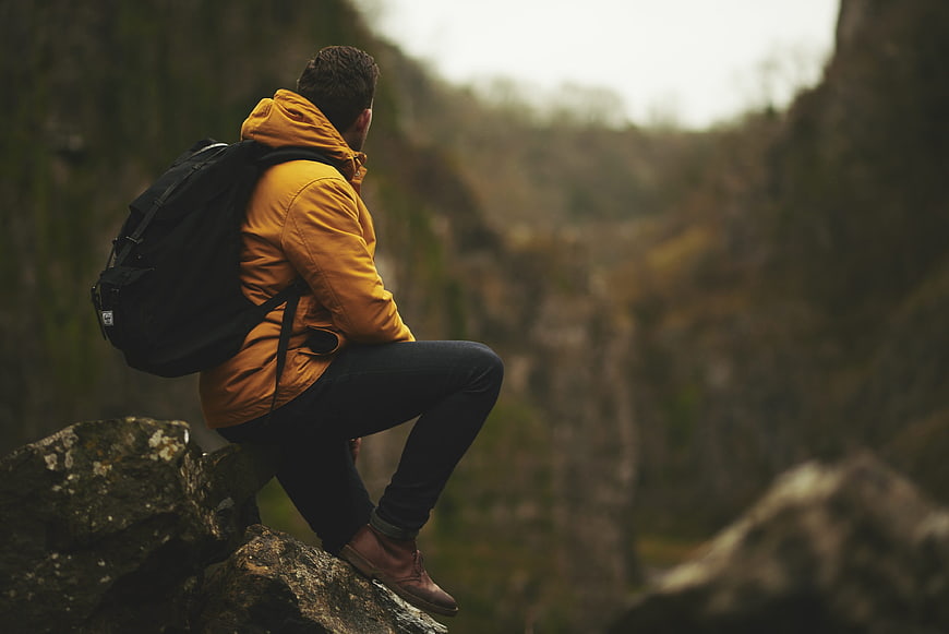Hiker in Yellow Jacket Sitting on Rock Overlooking Canyon