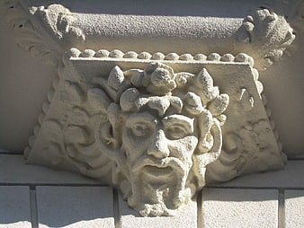 Close-up of ornate stucco face relief on building facade