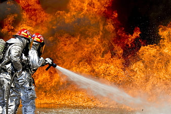 Firefighters in silver suits extinguishing massive fire