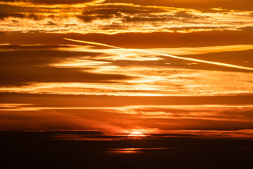 Dramatic Orange Sunset Sky With Layered Clouds And Horizon