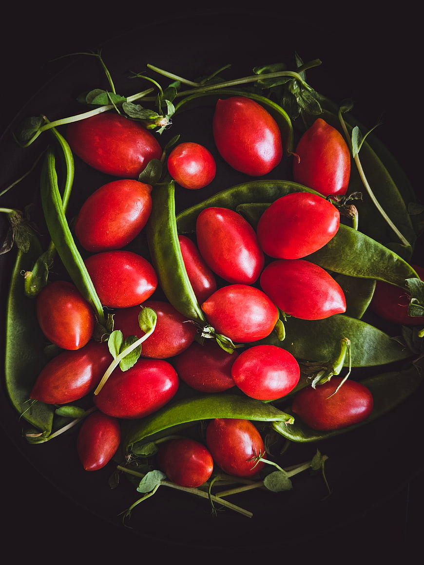 Top View of Red Tomatoes and Green Peas on Dark Background