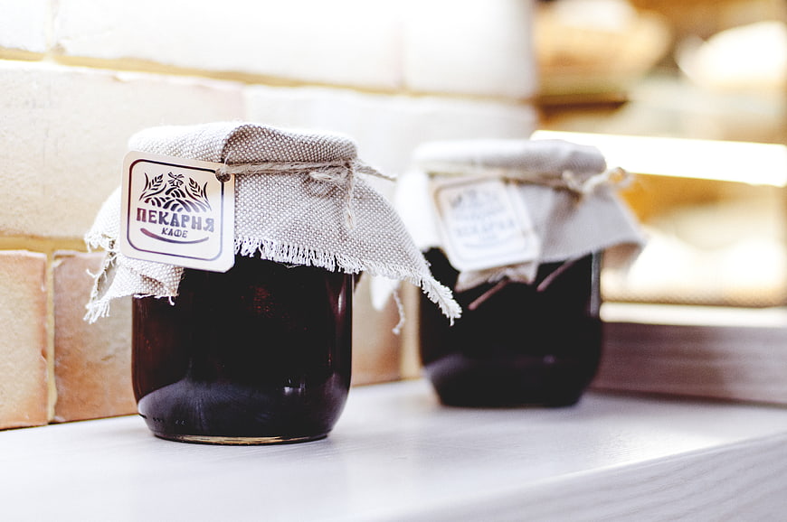 Artisanal jam jars with rustic labels on white shelf
