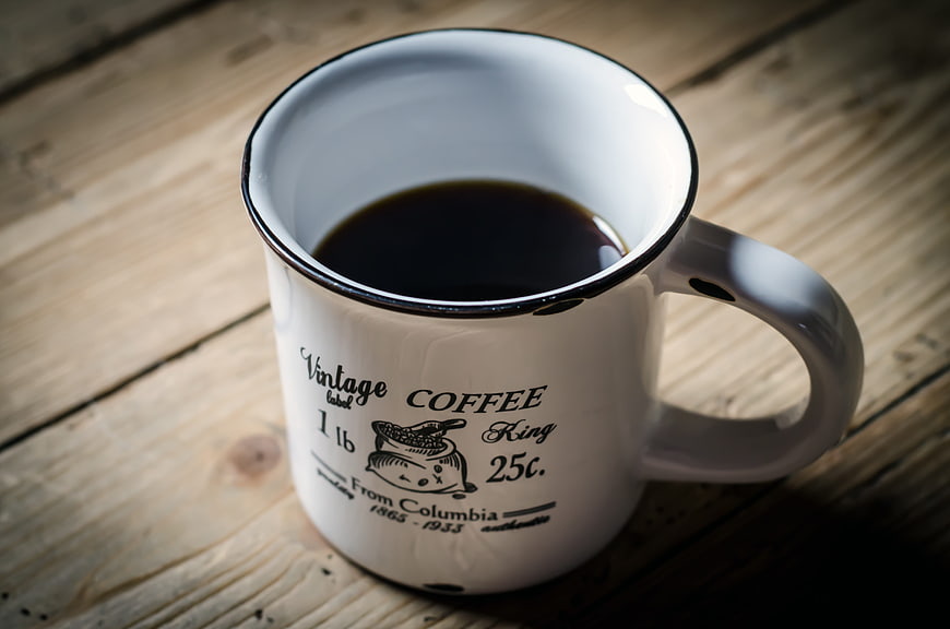Vintage enamel coffee mug on rustic wooden table