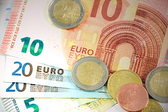 Euro banknotes and coins scattered on white background