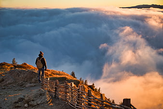 Hiker on Mountain Ridge Above Sea of Clouds at Golden Hour
