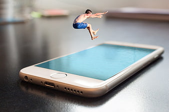 Miniature man jumping into smartphone screen pool