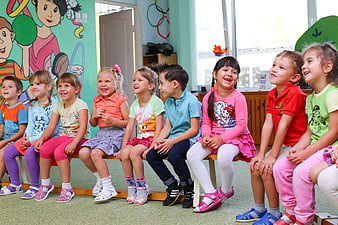 Happy children sitting in a row at kindergarten