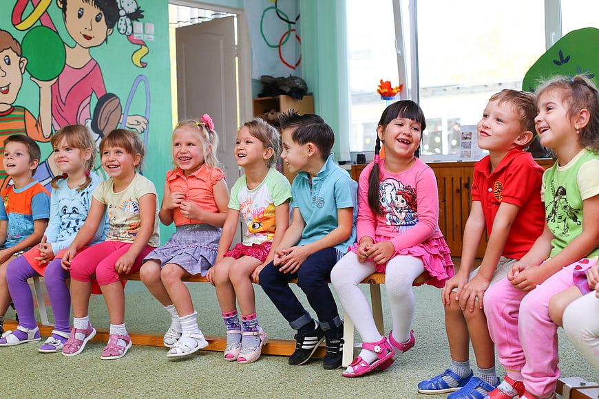 Happy children sitting in a row at kindergarten
