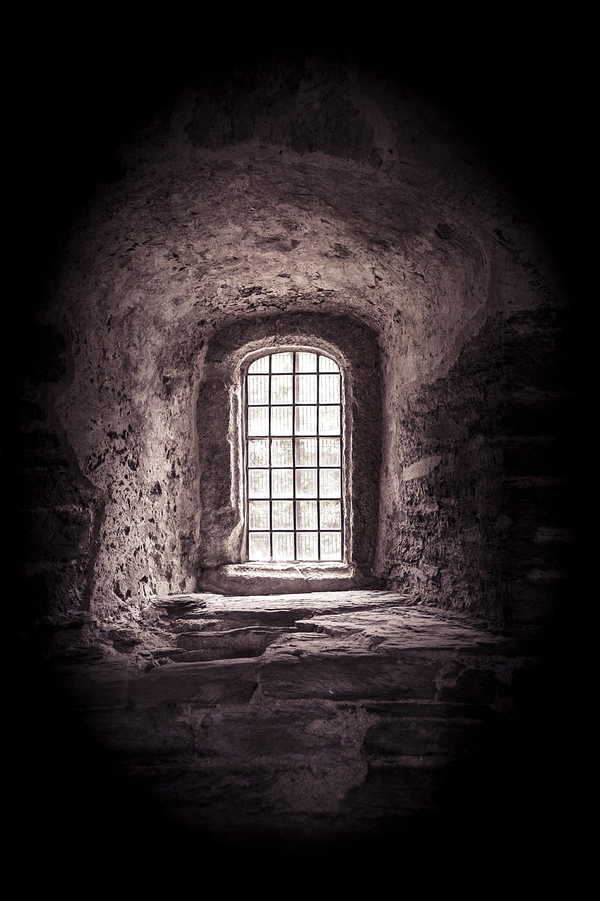 Dark medieval stone room with arched window