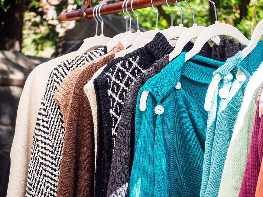 Colorful Knit Sweaters Hanging on Outdoor Clothes Rack