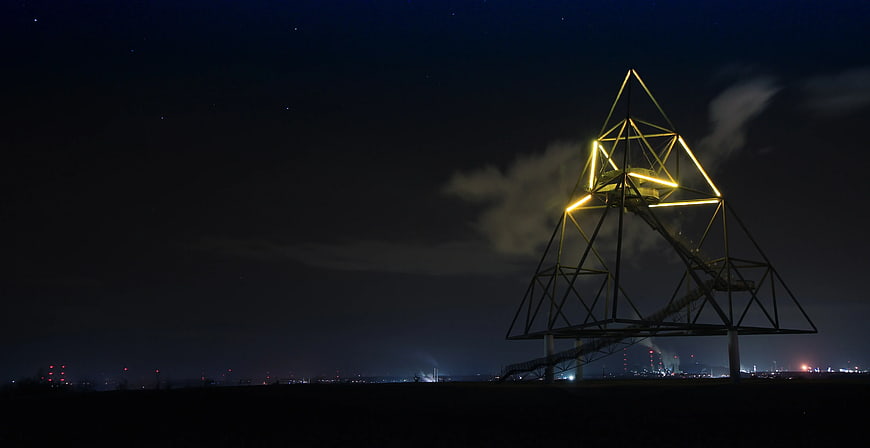 Illuminated Pyramid Structure at Night with City Lights