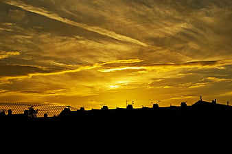 Golden sunset sky over city silhouette with clouds