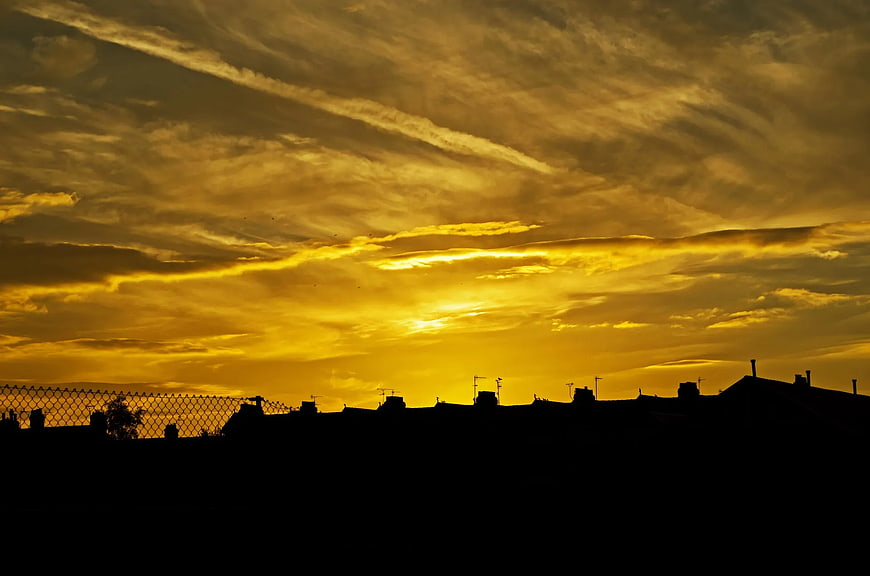Golden sunset sky over city silhouette with clouds