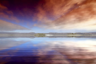 Dramatic sunset sky reflected in calm water landscape