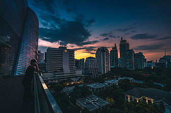 Man on Balcony Overlooking City Skyline at Sunset