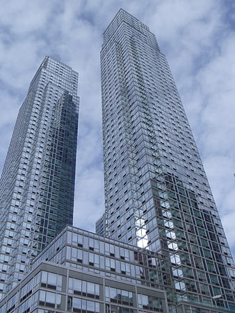 Low angle view of modern glass skyscrapers against cloudy sky