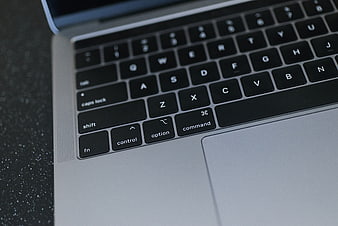 Close-up of MacBook keyboard and trackpad on dark surface