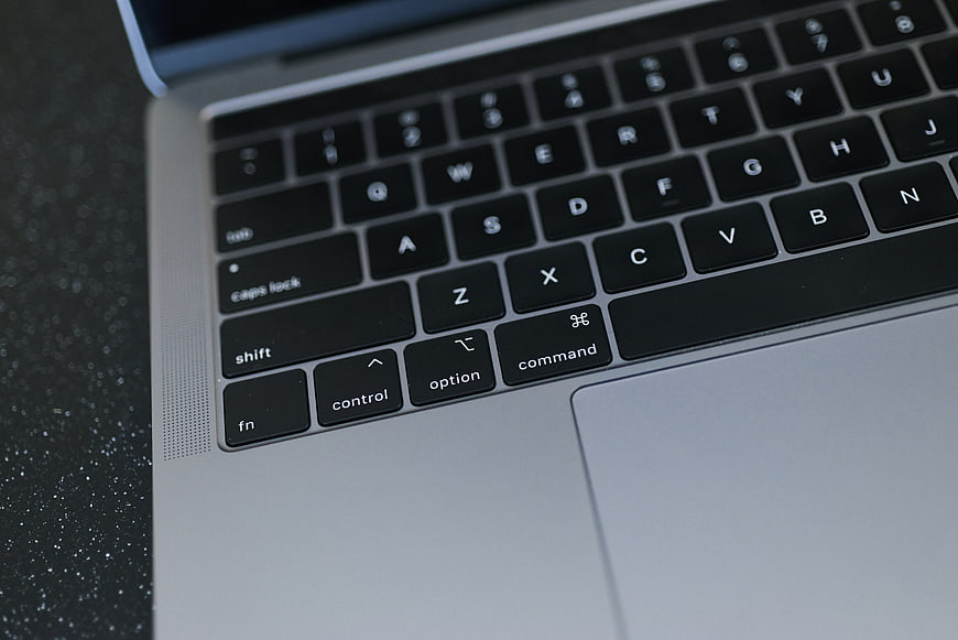 Close-up of MacBook keyboard and trackpad on dark surface