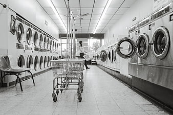 Black and white laundromat interior with washing machines and carts