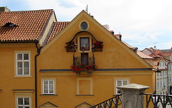 Yellow historic building facade with red flowers in Prague