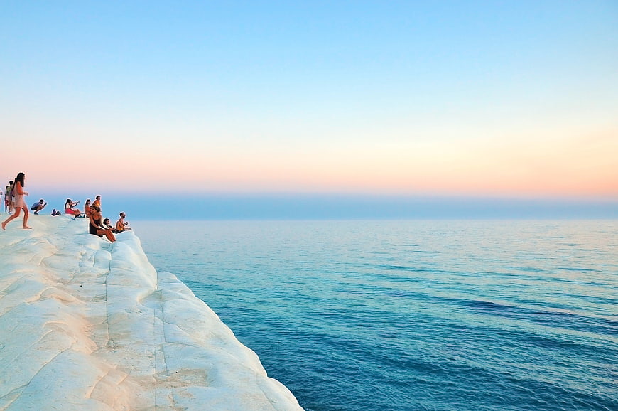 People relaxing on white Pamukkale travertines at sunset